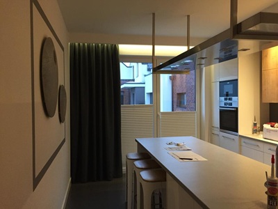Eine moderne K&uuml;che mit einem gro&szlig;en Fenster, das mit einem dunklen, weichen Vorhang verdeckt ist